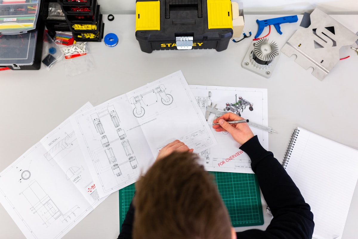 An engineer checking a printed drawing against a part with calipers